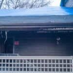 The outside of a home with the roof and porch damaged due to a recent fire. There’s a blue tarp over part of the roof.